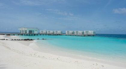 Luxurious overwater villas on a pristine beach with turquoise waters and clear blue skies.