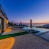 Serene coastal villa view with infinity pool and stunning sunset over the sea.