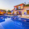 Elegant stone villa with illuminated facade, pool, and relaxing outdoor area.