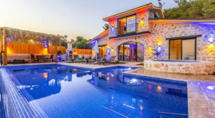 Elegant stone villa with illuminated facade, pool, and relaxing outdoor area.